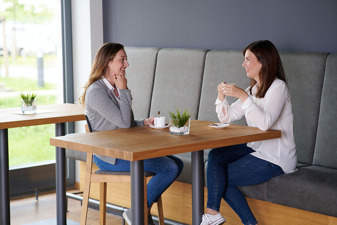 Zwei junge Frauen unterhalten sich in Betriebsrestaurant