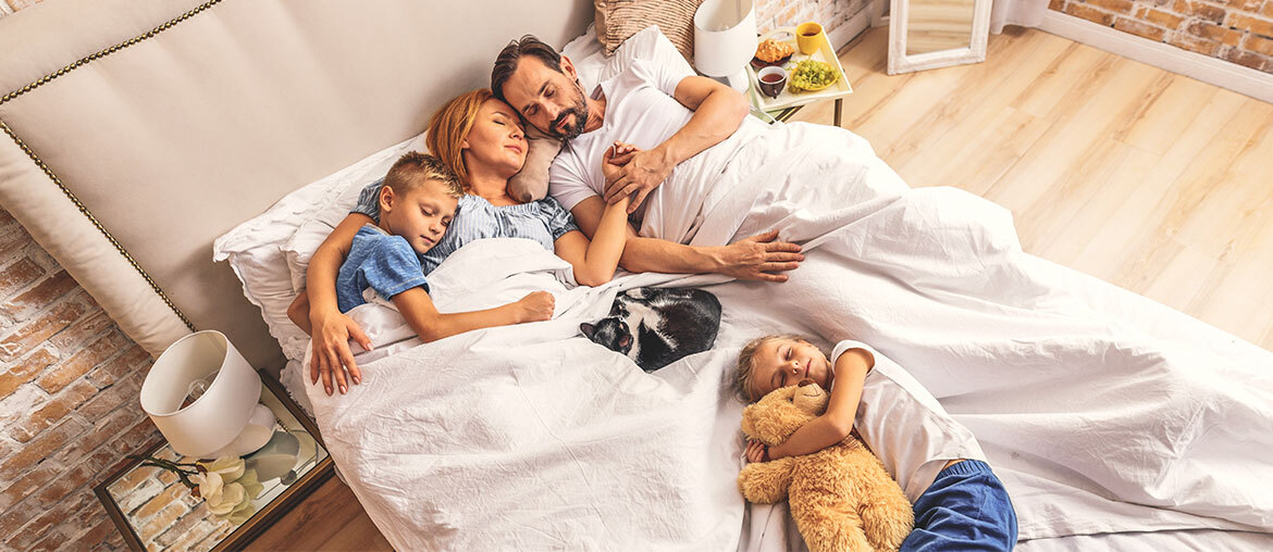 Vierköpfige Familie liegt gemeinsam im Bett und schläft
